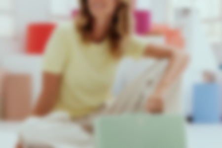 Una mujer está sentada en el suelo con un altavoz bluetooth BOOMSTER 4 verde.