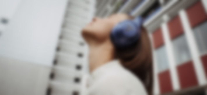 Junge Frau in Berlin mit dem REAL BLUE NC 3 in Steel Blue auf dem Kopf schaut nach oben und hört Musik