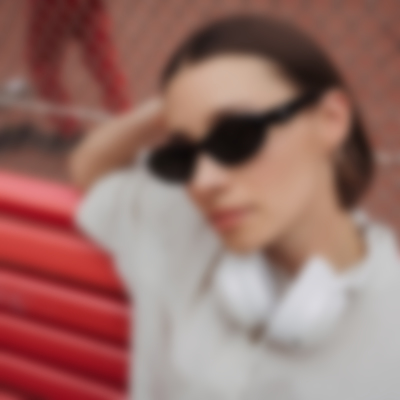 Galerie Bild 13 von 20 Junge Frau mit Sonnenbrille auf einer Bank trägt den REAL BLUE NC 3 in Pearl White um den Hals