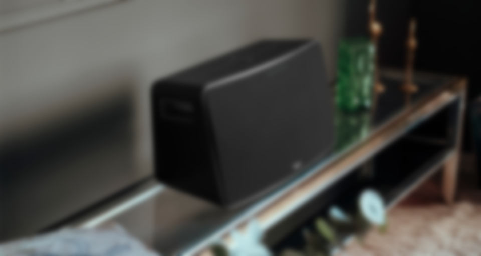 Une enceinte wifi MOTIV XL noire et élégante repose sur une table brillante.