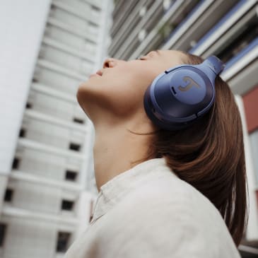 Junge Frau in Berlin mit dem REAL BLUE NC 3 in Steel Blue auf dem Kopf schaut nach oben und hört Musik