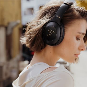 Eine junge Frau trägt draußen stylische schwarze REAL BLUE PRO Kopfhörer.