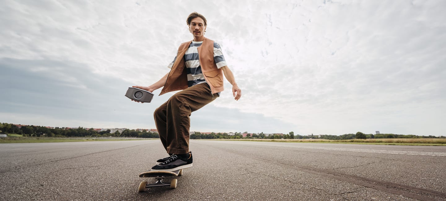 Mann auf Skateboard mit Rockster GO 2 in der Hand
