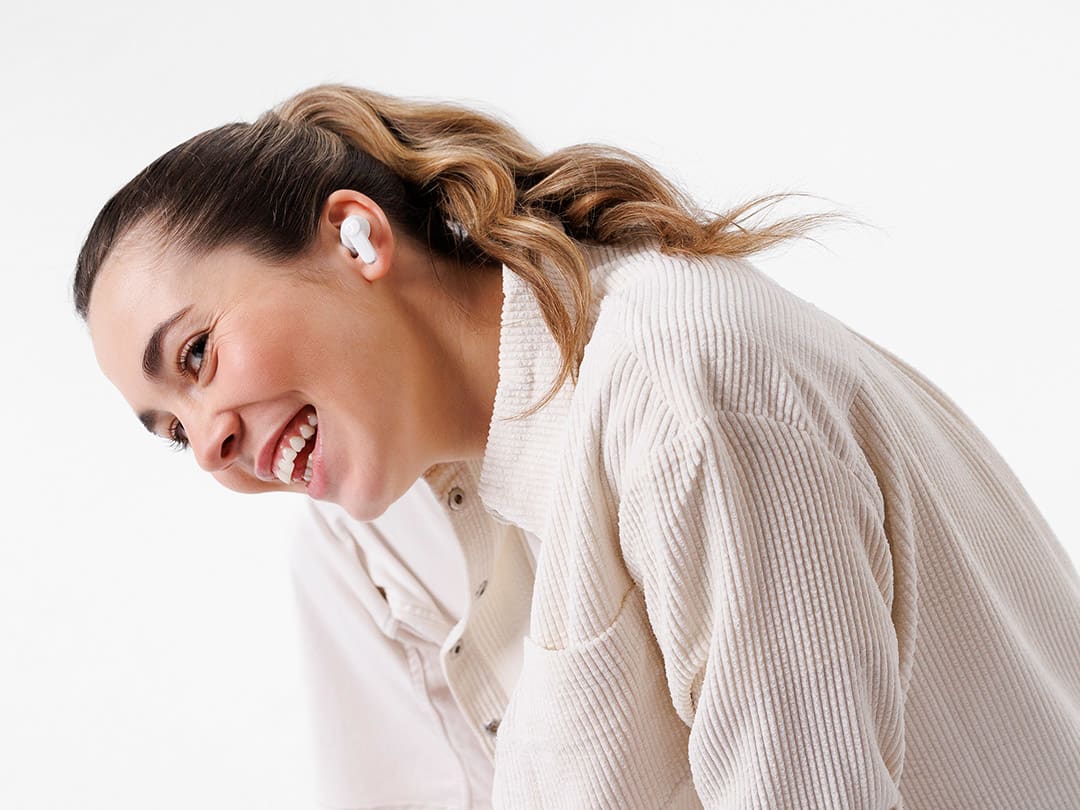 A woman wears white wireless AIRY TWS 2 earbuds.